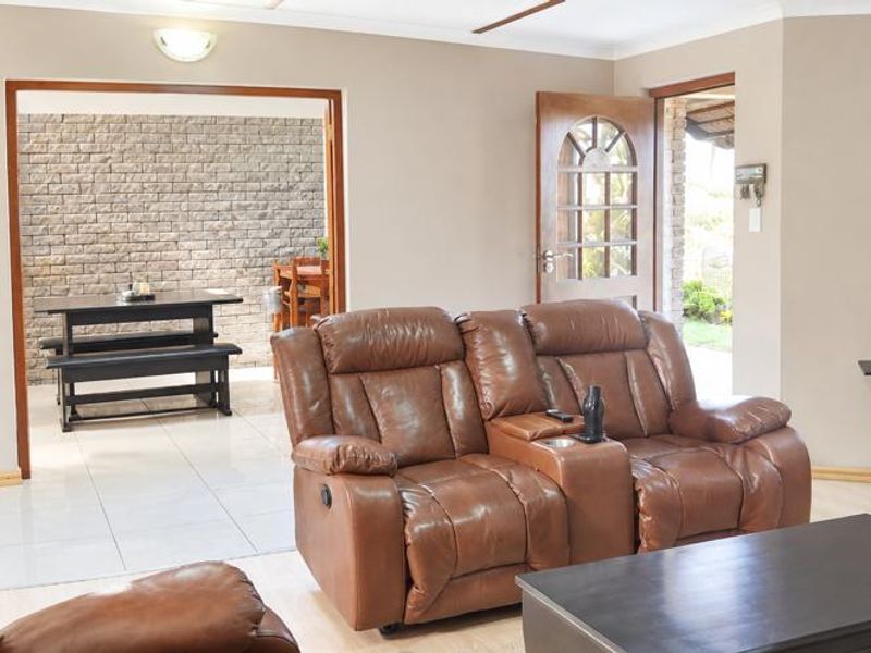 Spacious living area featuring a mix of tiled and laminate flooring, with a transition into an adjacent dining space and access to the exterior.
