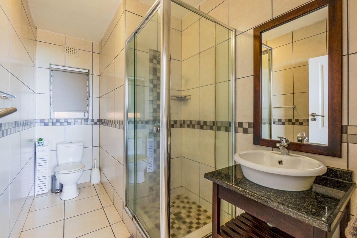 A functional bathroom featuring a glass-enclosed shower, a vanity with a granite countertop, a vessel sink, and a toilet.
