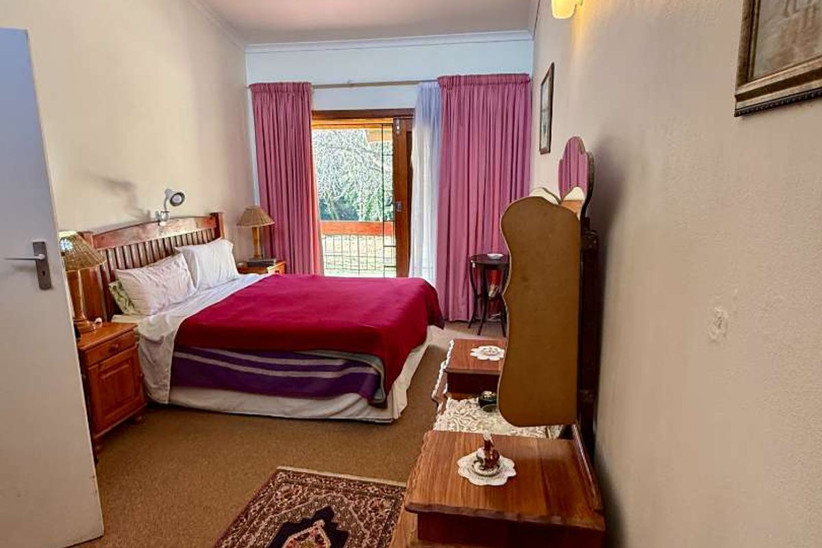 A bedroom featuring carpeted flooring, wall-mounted lighting, and a sliding door providing access to an outdoor balcony area.