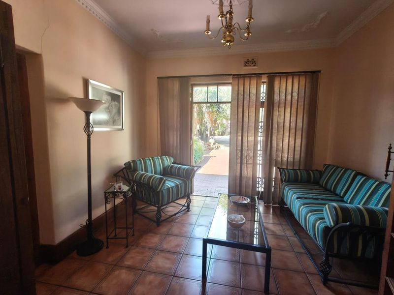 A living room featuring tiled flooring, decorative ceiling details, and a sliding glass door providing access to the outdoor area.