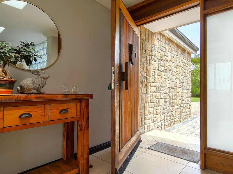 Welcoming entrance hall featuring a solid timber front door, tiled flooring, and a view of the exterior stone-clad facade.