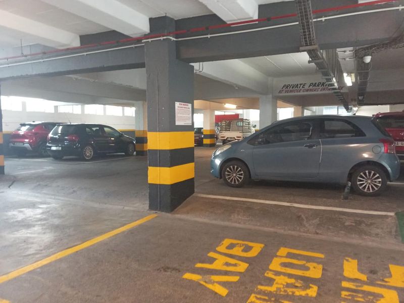 A functional indoor parking garage featuring concrete structural columns, exposed ceiling infrastructure, and clearly marked parking bays.