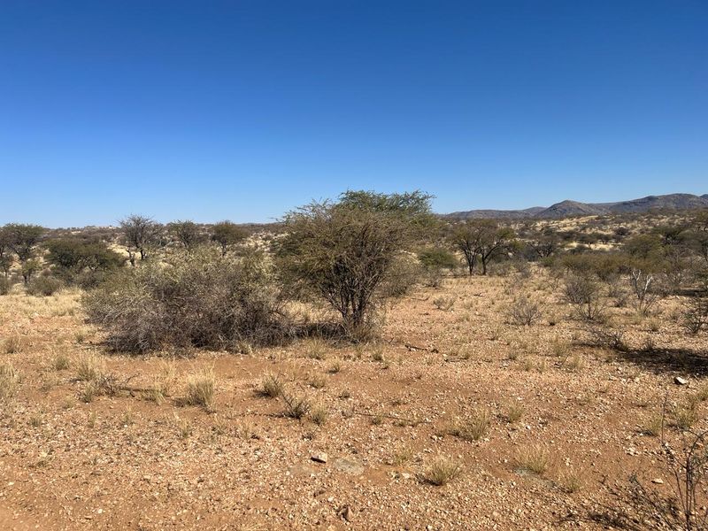 A wide-angle view of the vacant residential land featuring natural arid landscape, native shrubs, and distant mountain vistas.