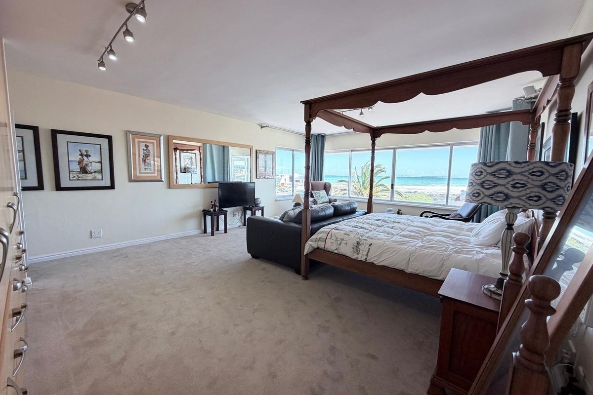 Spacious bedroom featuring large windows with ocean views, neutral carpet flooring, track lighting, and built-in storage.
