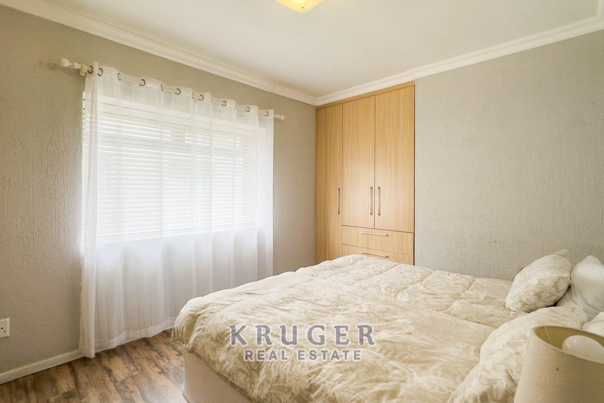 A well-maintained bedroom featuring built-in wooden cabinetry, textured wall finishes, and wood-look flooring, providing a clean and functional living space.