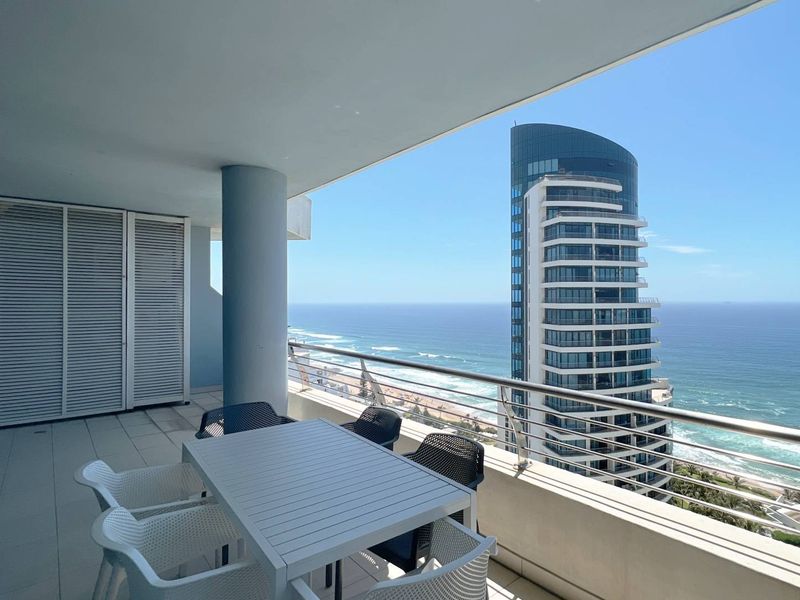 Spacious covered balcony featuring tiled flooring, a stainless steel balustrade, and panoramic ocean and city views.