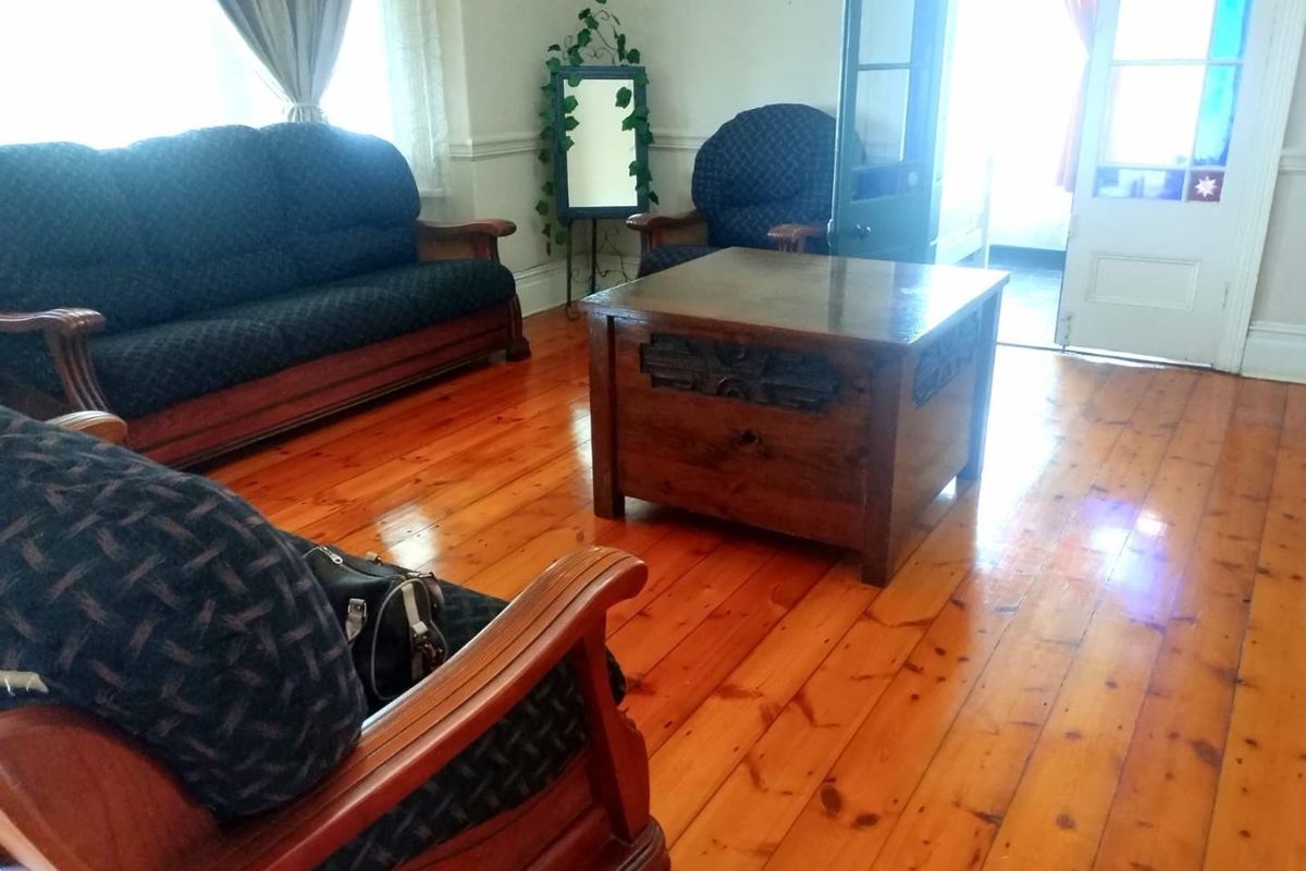A living room featuring polished timber flooring and classic french doors, providing a warm and traditional atmosphere.