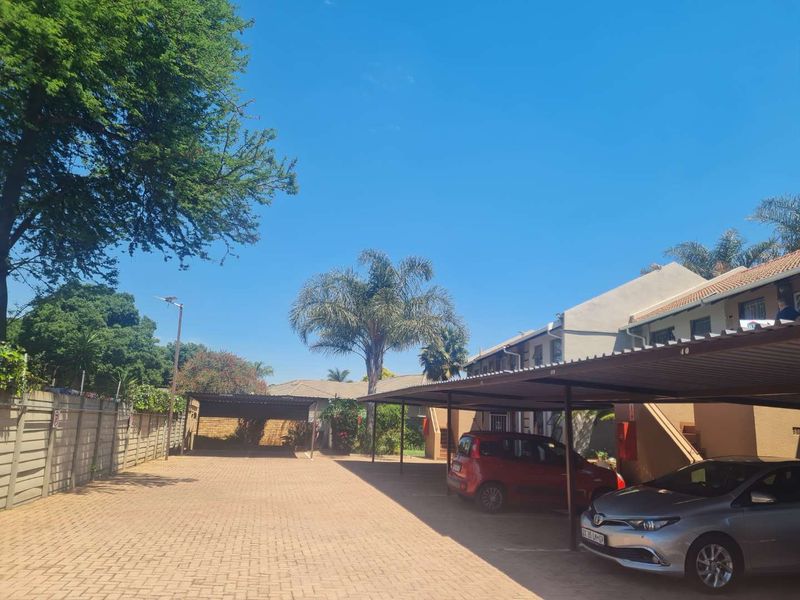 Exterior view of the apartment complex featuring a paved driveway and covered parking bays.