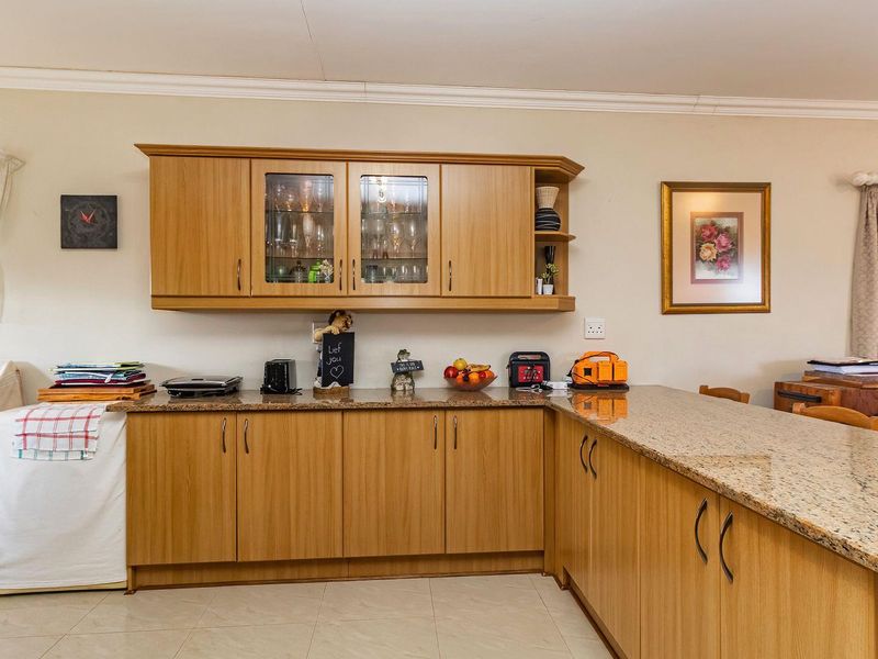A functional kitchen featuring light wood-finish cabinetry, granite countertops, and tiled flooring, offering ample storage and workspace.