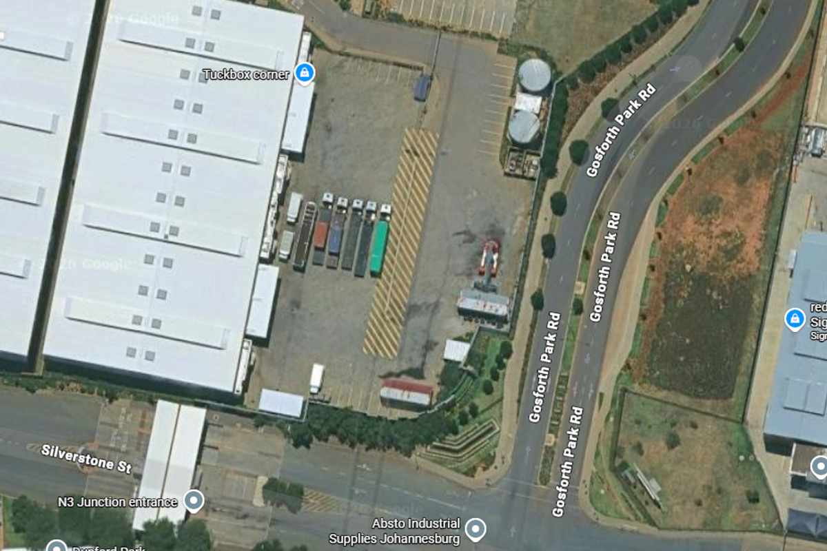 Aerial view of an industrial property featuring a large warehouse facility, paved yard space, and direct access to major road infrastructure.