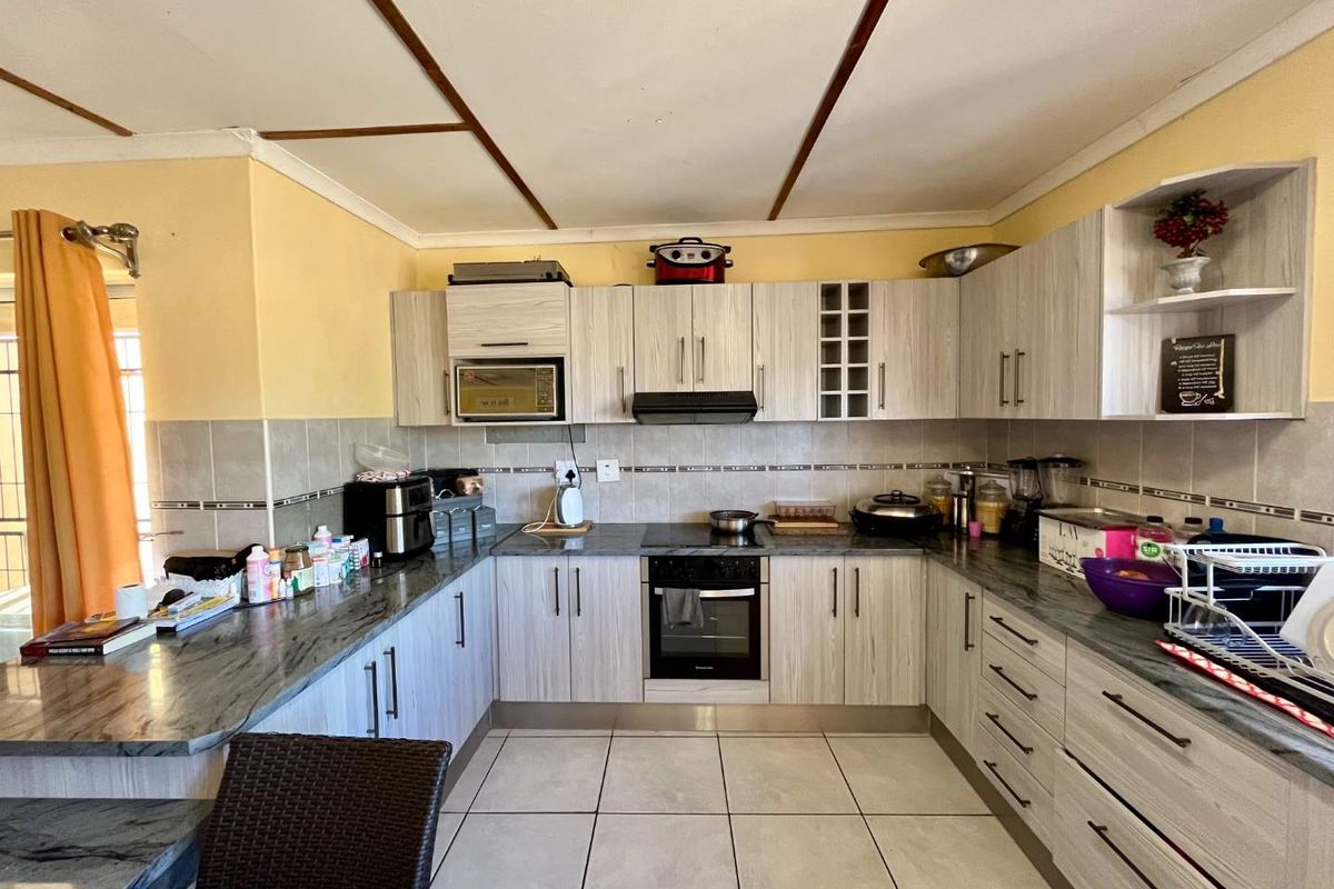 A functional U-shaped kitchen featuring light wood-grain cabinetry, granite-look countertops, tiled backsplash, and integrated oven and hob.