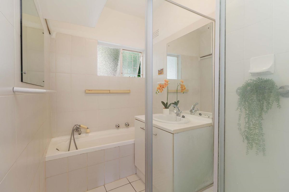A functional bathroom featuring a built-in bathtub, a vanity cabinet with an integrated sink, and a separate shower enclosure with tiled finishes.