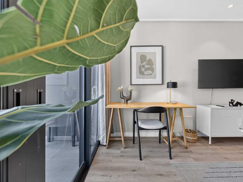 A bright living area featuring modern laminate flooring, recessed lighting, and large sliding glass doors that provide ample natural light.
