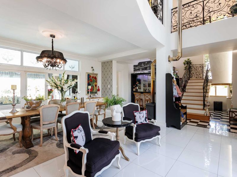 Spacious open-plan living and dining area featuring high ceilings, a mezzanine level with ornate wrought iron railings, and a built-in bar.