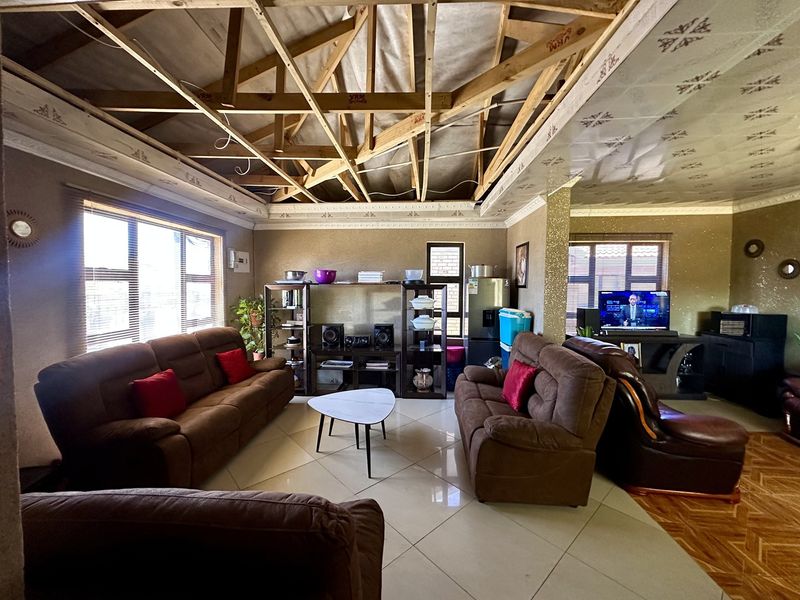 Open plan living area featuring tiled floors and large windows, currently requiring ceiling completion and finishing to reach its full potential.