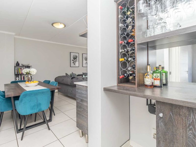 Open plan living and dining area featuring a built-in bar unit with integrated wine storage and neutral tiled flooring throughout.