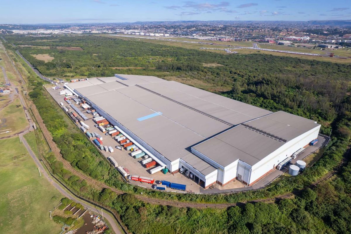 Aerial view of a large industrial warehouse facility featuring extensive loading bays, expansive roof structure, and surrounding logistics yard.