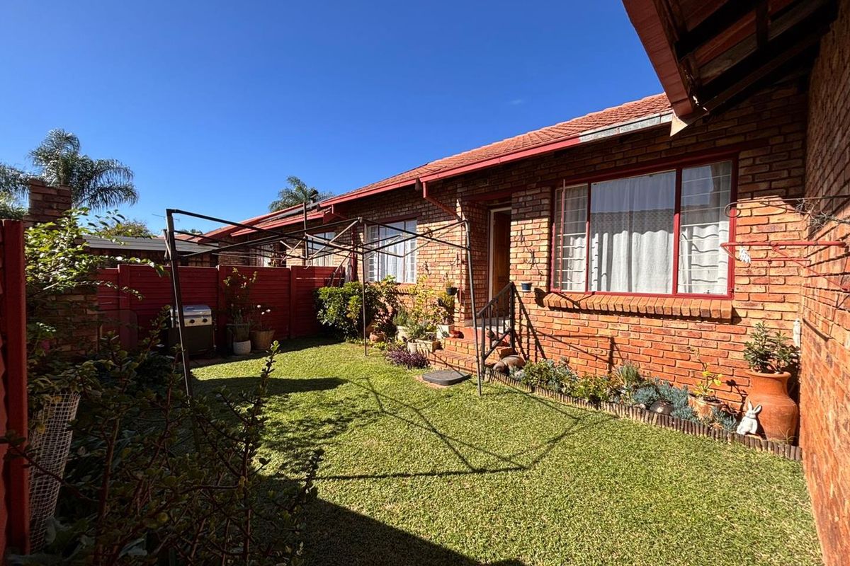 A private rear garden featuring a well-maintained lawn, brick facade, and secure perimeter fencing, providing a quiet outdoor space for the townhouse.