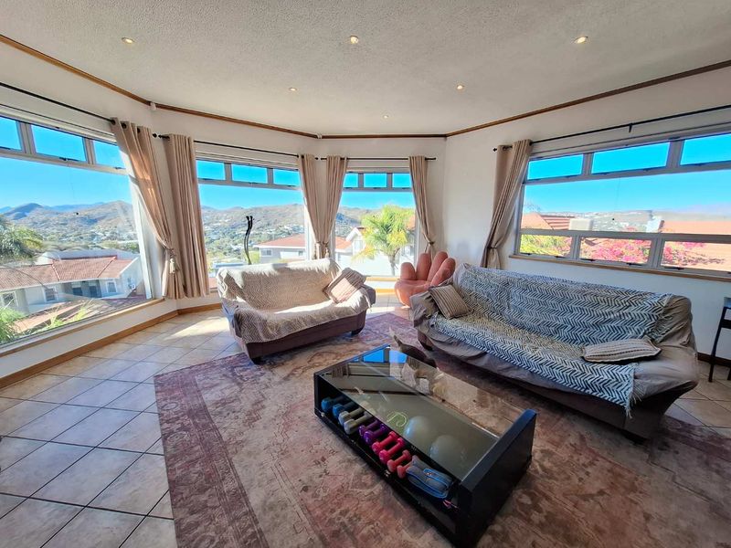 Spacious living room featuring extensive panoramic windows that offer abundant natural light and scenic mountain views, complemented by tiled flooring and recessed lighting.