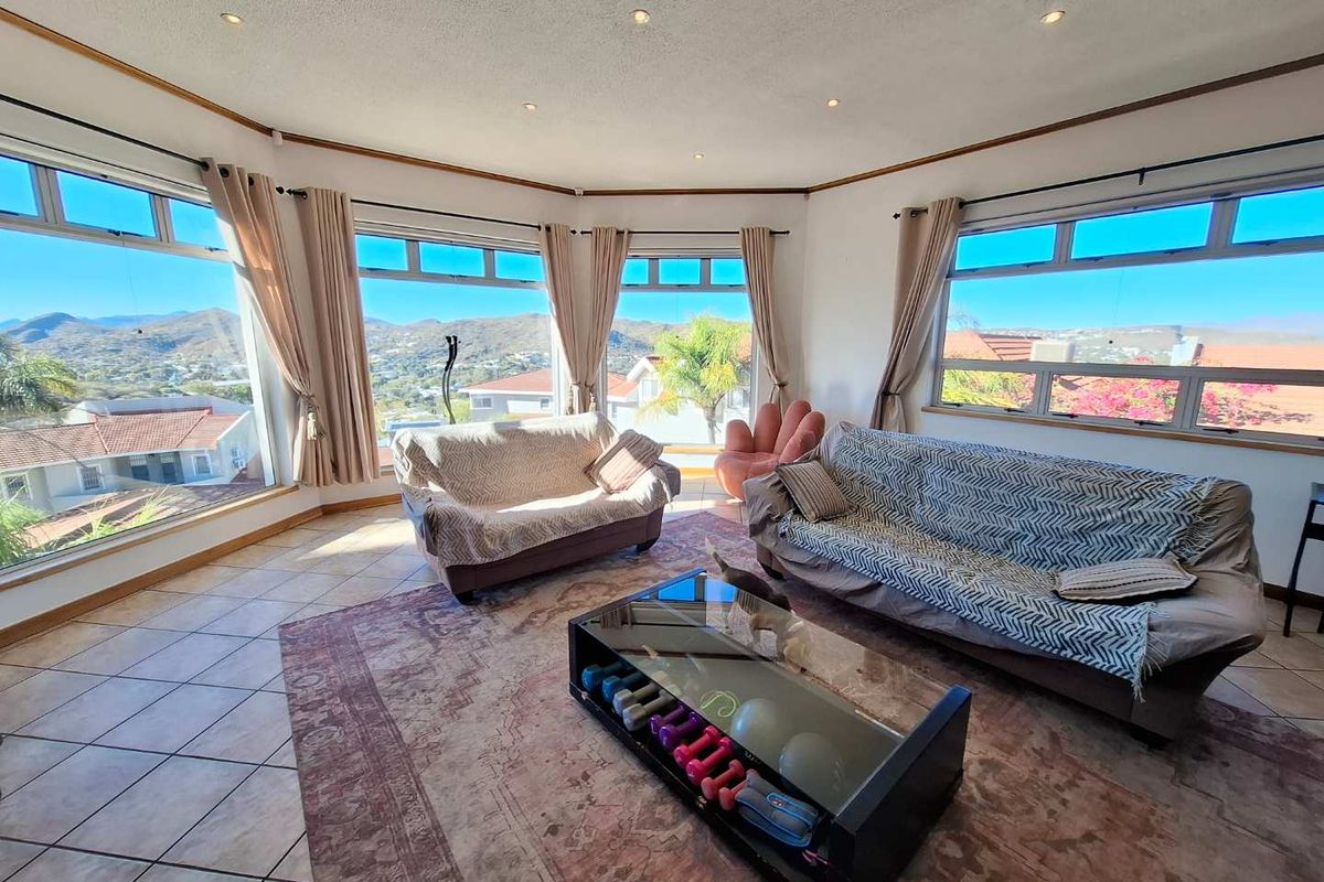 Spacious living room featuring extensive panoramic windows that offer abundant natural light and scenic mountain views, complemented by tiled flooring and recessed lighting.