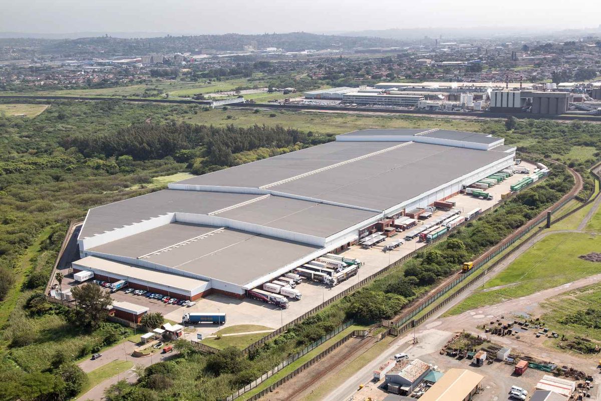 Aerial view of a large industrial warehouse facility featuring extensive loading bays, paved yard space, and secure perimeter fencing.