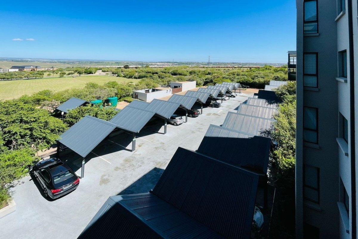Aerial view of the apartment complex parking area featuring covered carports and landscaped surroundings.