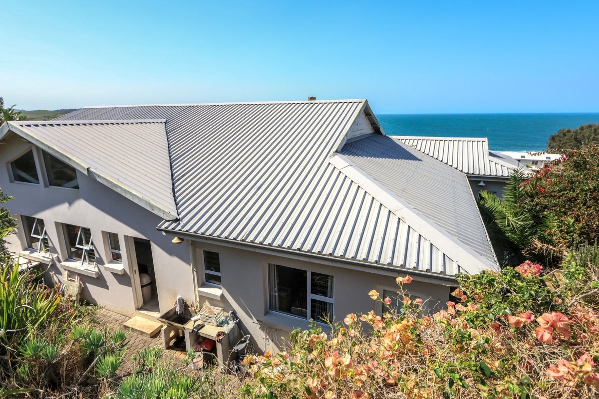 Aerial view of a coastal farm property featuring a corrugated metal roof, exterior masonry walls, and scenic ocean views.
