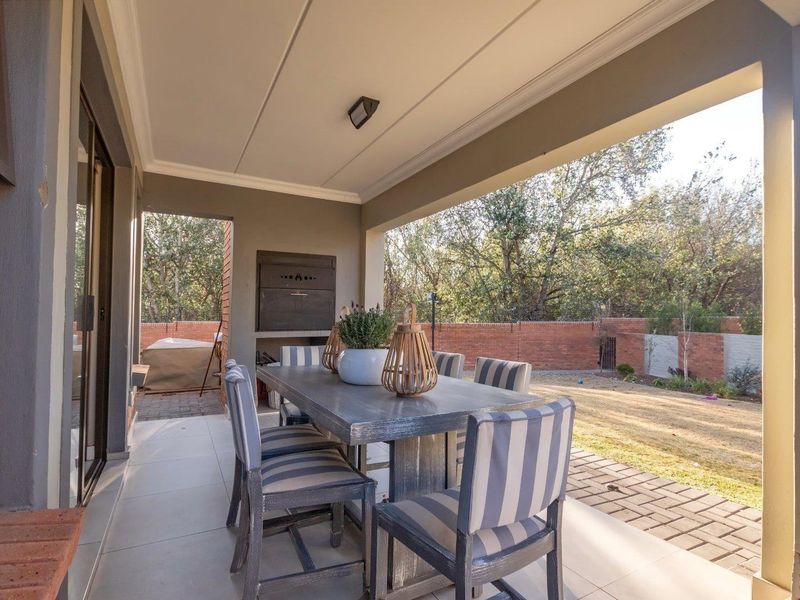 Covered patio featuring a built-in braai, tiled flooring, and direct access to the garden area through sliding doors.