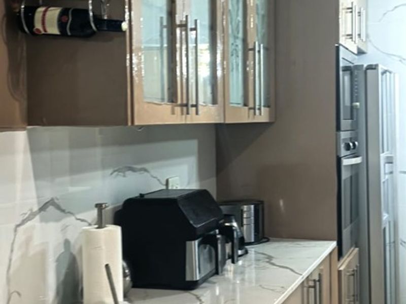 Modern kitchen featuring sleek cabinetry, stone countertops with marble-effect detailing, and integrated oven appliances.