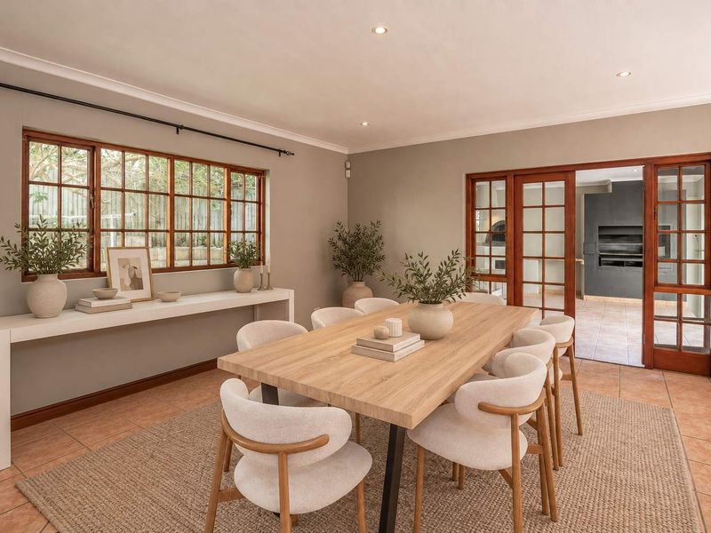 A bright and well-maintained dining room featuring tiled flooring, coved cornicing, and wooden framed windows and doors leading to an adjacent area.