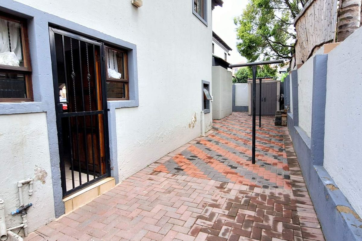 Side exterior area featuring paved flooring, security gate access, and a fixed washing line structure.