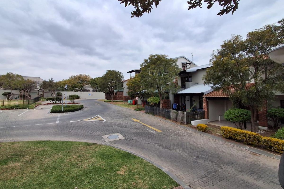 A view of the apartment complex grounds featuring paved driveways, landscaped gardens, and residential building facades.