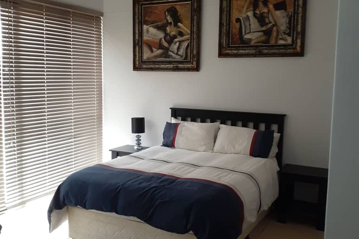 A well-lit bedroom featuring tiled flooring, venetian blinds, and a modern track lighting fixture.