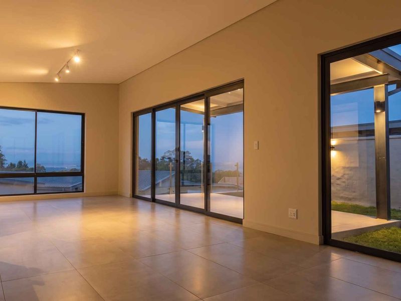 Spacious, modern living area featuring large aluminium sliding doors, neutral tiled flooring, and recessed lighting, offering seamless indoor-outdoor flow.