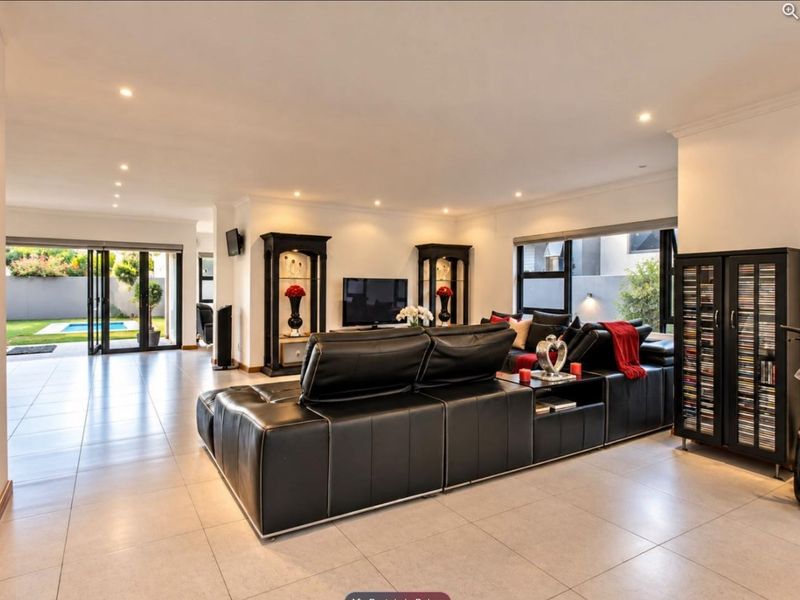 Spacious open-plan living area featuring neutral tiled flooring, recessed downlighting, and large aluminium sliding doors providing seamless access to the outdoor pool area.