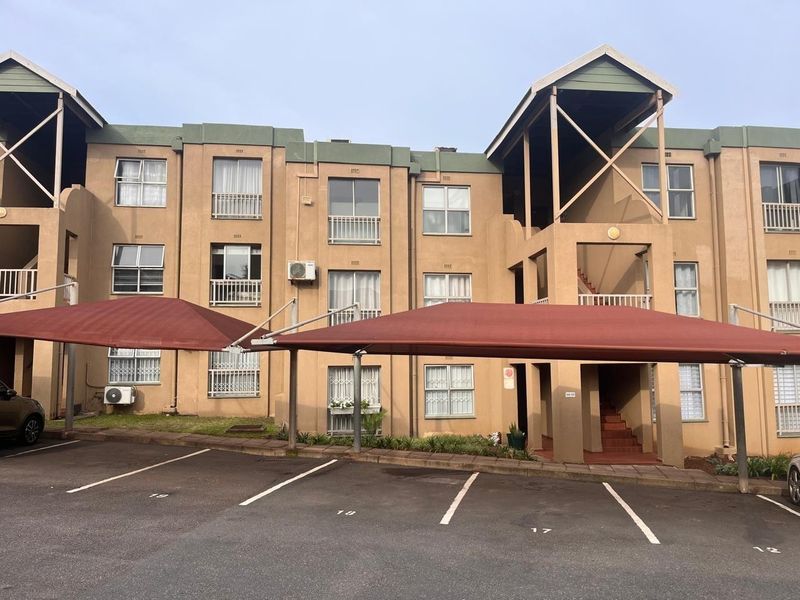 Front elevation of a multi-story apartment complex featuring covered parking bays, security-fitted windows, and external air conditioning units.