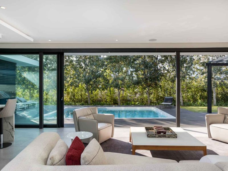 Modern open-plan living area featuring large sliding glass doors that provide seamless indoor-outdoor flow to the swimming pool and garden area.