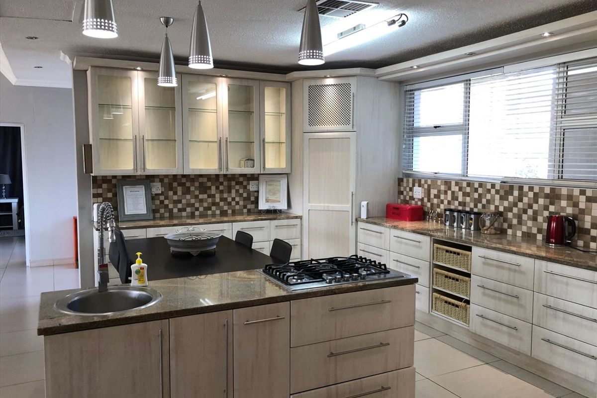 A well-appointed kitchen featuring a central island with a built-in gas hob and sink, complemented by ample cabinetry and tiled splashbacks.