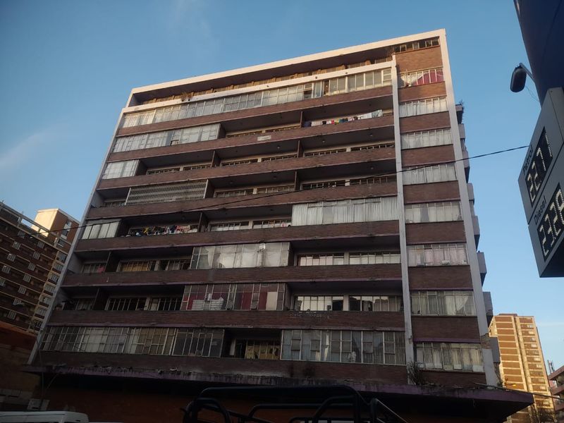 A multi-story apartment building featuring a brick facade with enclosed balcony sections and standard window configurations.