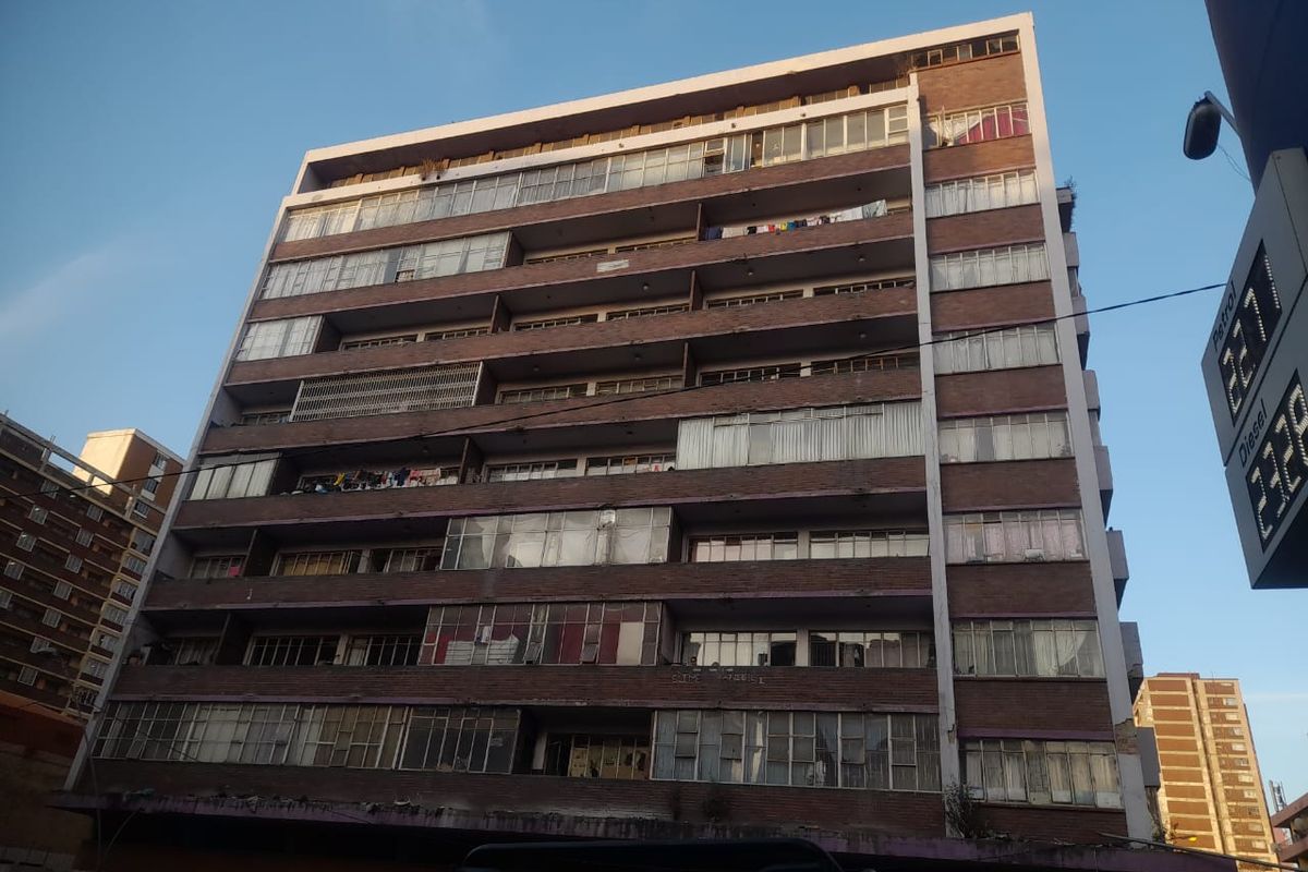 A multi-story apartment building featuring a brick facade with enclosed balcony sections and standard window configurations.