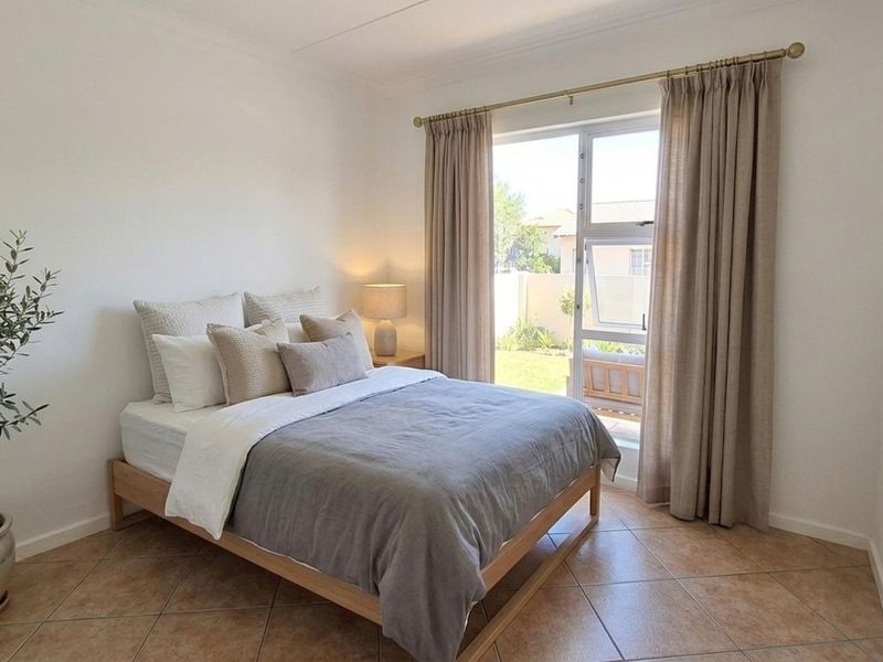 A bright and well-maintained bedroom featuring tiled flooring and a sliding glass door providing direct access to the garden area.
