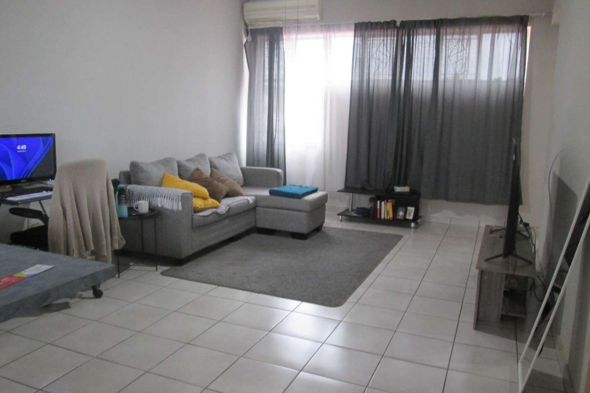 A spacious living room featuring tiled flooring and a wall-mounted air conditioning unit, providing a comfortable and functional living space.