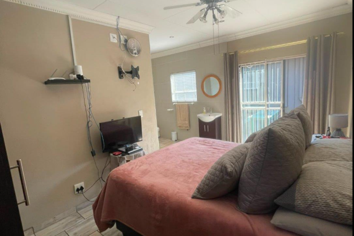 Bedroom featuring tiled flooring, ceiling fan, recessed lighting, and an integrated pedestal basin, with sliding door access to the exterior.