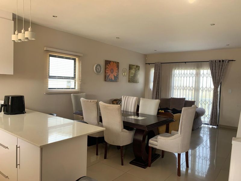 Spacious open-plan living and dining area featuring modern porcelain floor tiles, neutral walls, and a functional kitchen island with quartz countertops.