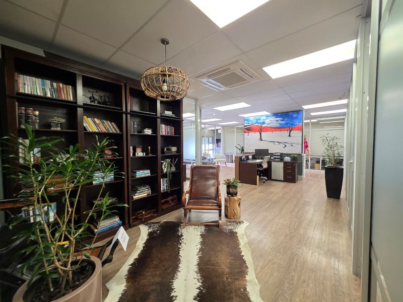 Modern office space featuring glass partitions, suspended ceilings with recessed lighting, ducted air conditioning, and durable wood-look flooring.
