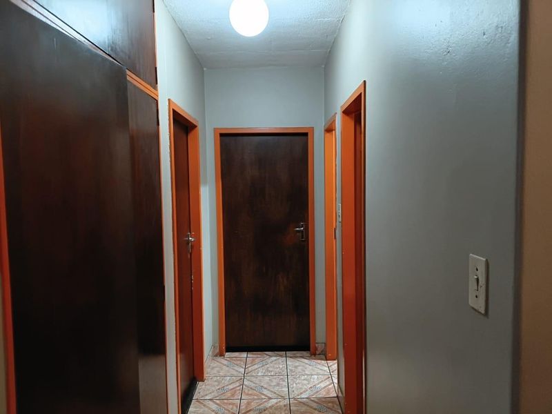 A functional hallway featuring tiled flooring, built-in storage cupboards, and multiple wooden doors leading to adjacent rooms.