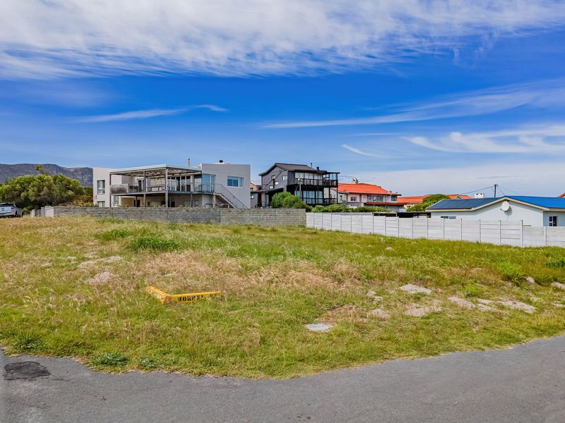 A vacant residential plot situated on a corner lot, featuring street access and established boundary walls in a developed neighborhood.