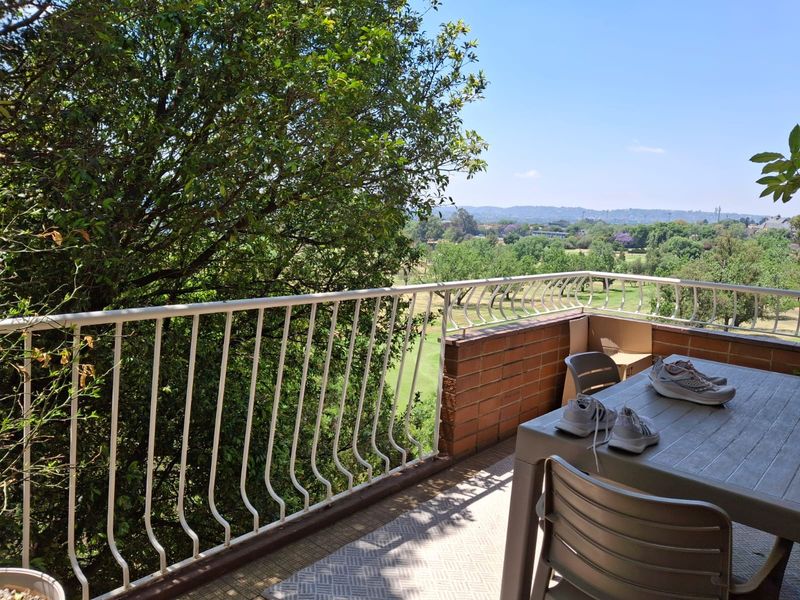A balcony featuring a metal balustrade and brick wall, offering scenic views of the surrounding landscape and greenery.