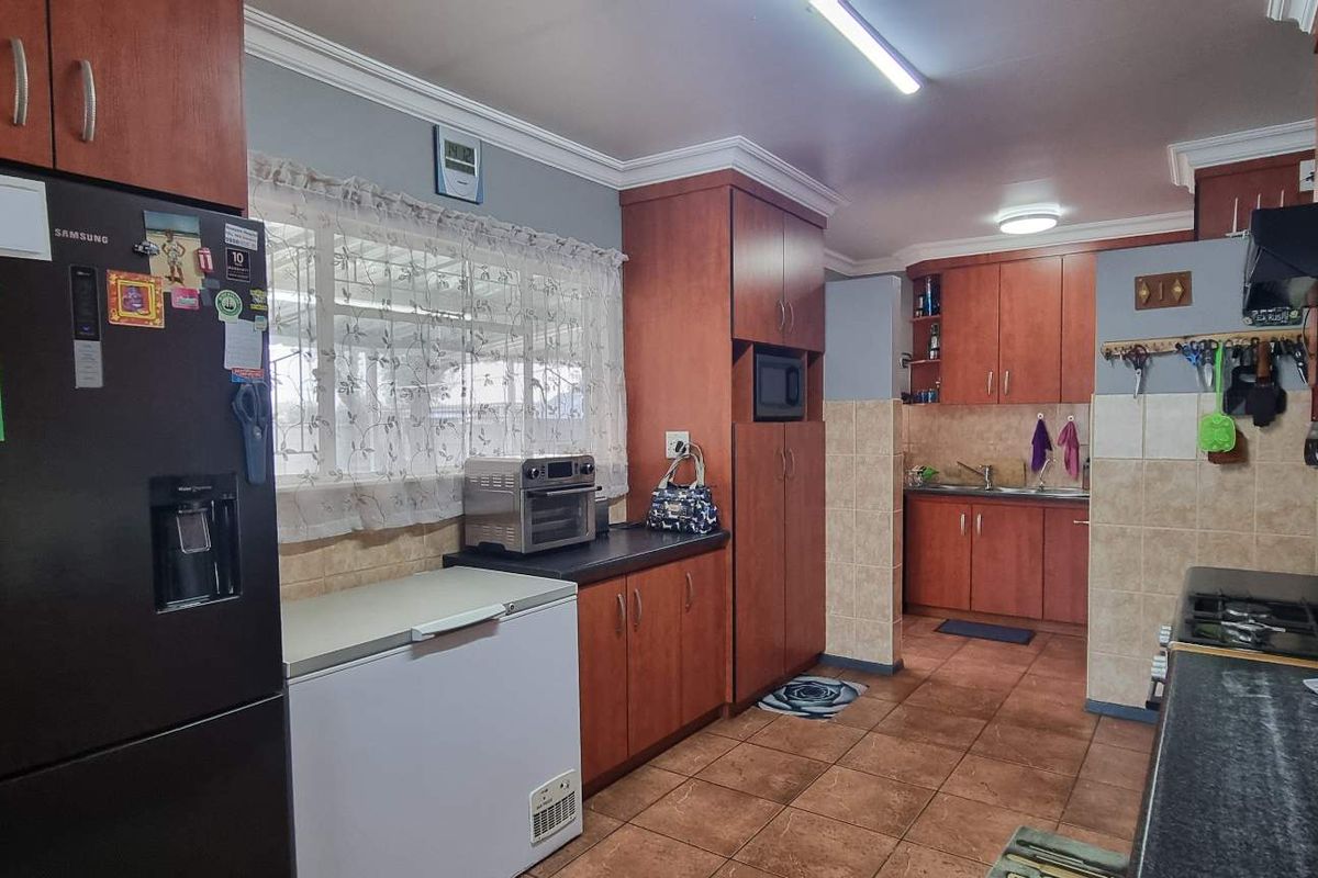 A functional kitchen featuring wooden cabinetry, tiled flooring, and a built-in gas hob, offering ample storage and workspace for daily meal preparation.