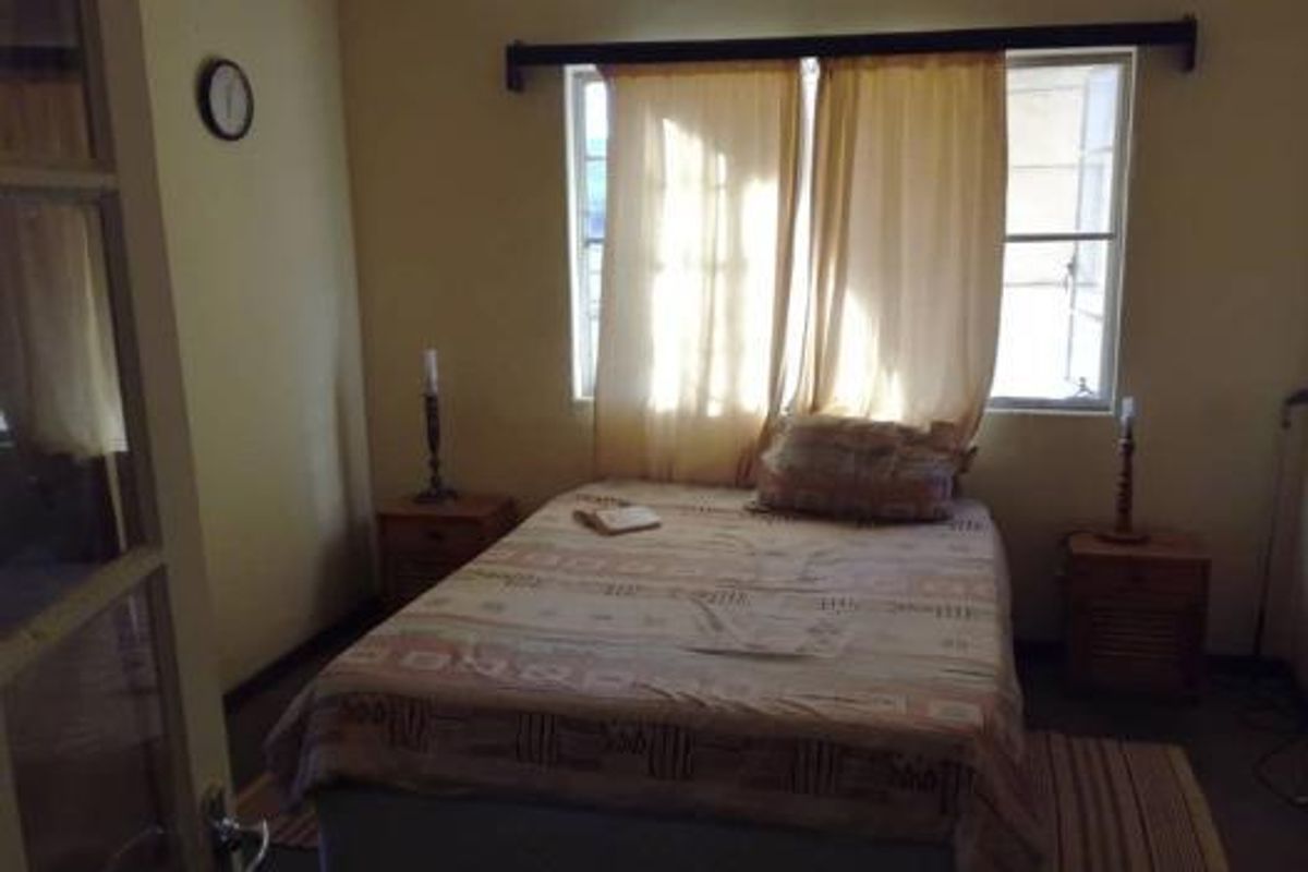 A functional bedroom featuring a window with curtain rod and neutral wall finishes.
